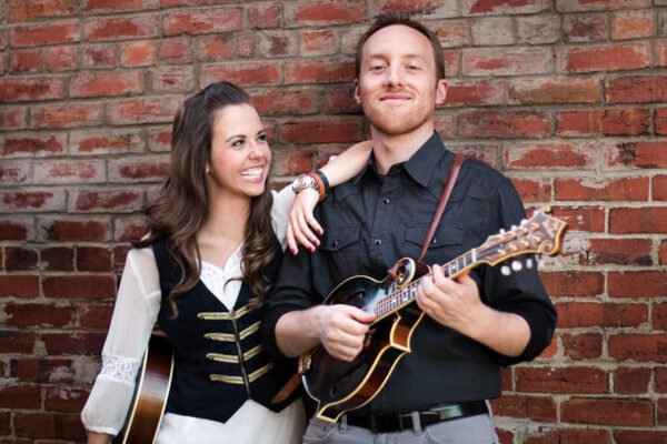 Two people holding mandolins. One Women, One Man. Woman looking up at the man while smiling.